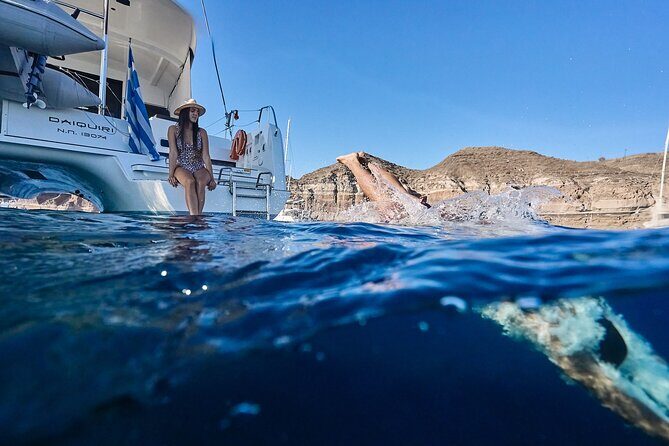 Santorini: Caldera Private Catamaran Cruise with Meal & Drinks - Stop 1: Red Beach from the boat, with a quick swim window